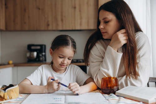 Giovane ragazza disegna con la madre al suo fianco